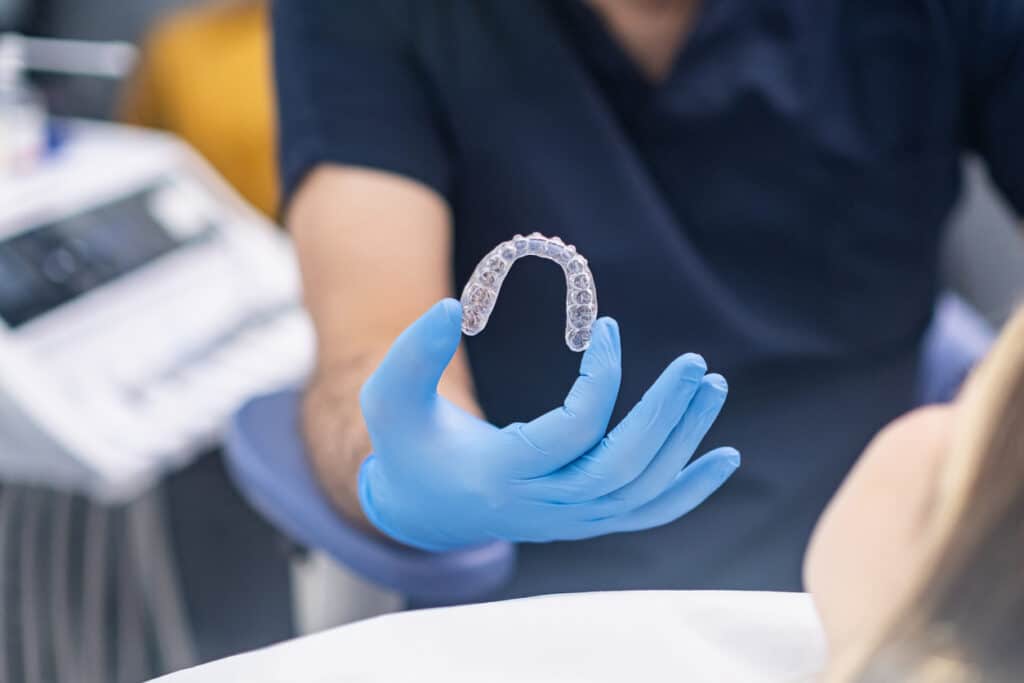 Invisalign in Fulham dentist holding braces