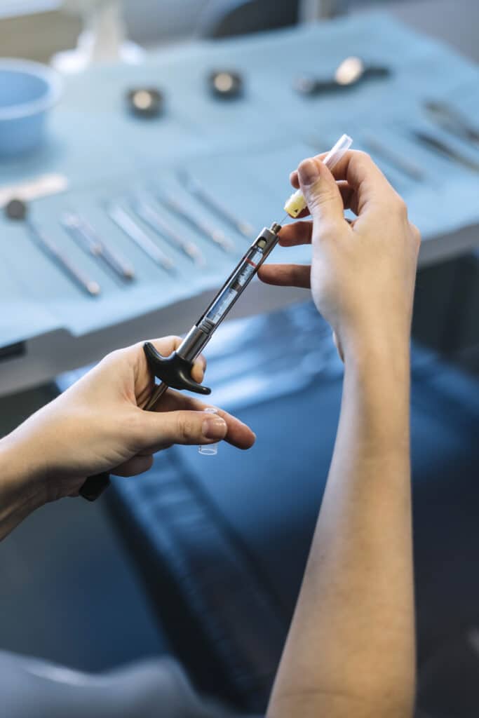 Dentist's hands preparing a surgical syringe